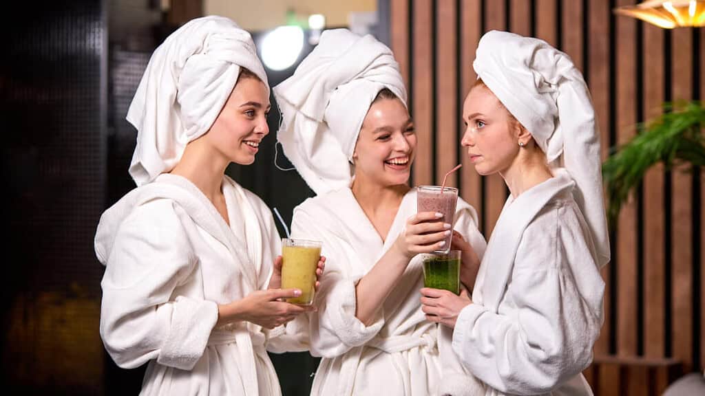 Freundinnen genießen einen Tag im SPA zusammen und trinken Smoothies.