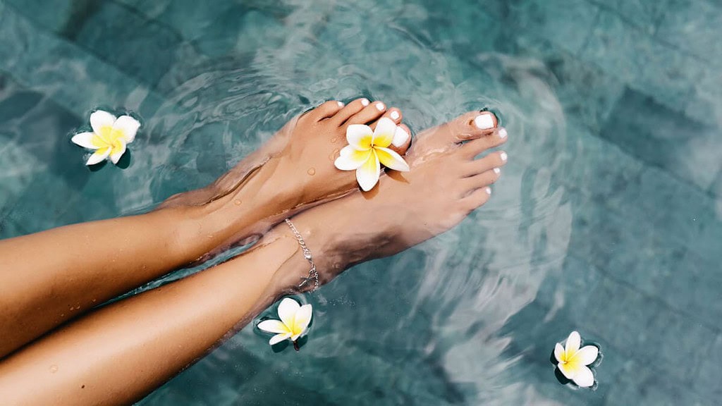 fusspflege-spa-behandlung Ästhetisch ansprechende Aufnahmen in einem Schwimmbad mit auf der Wasseroberfläche schwimmenden Plumerien