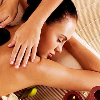 Eine Frau liegt auf einem Massagebett mit heißen Steinen auf ihrem Rücken