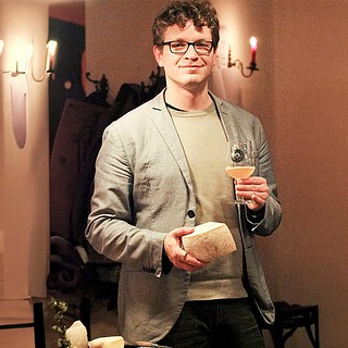 Eine Person steht in der Mitte mit einem Glas Bier und Käse in der Hand beim Bier- und Käseseminar in Leipzig