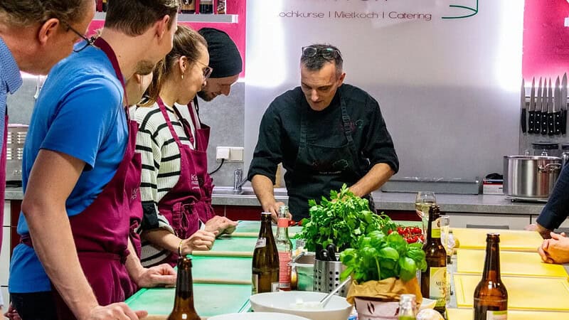 Der Profikoch zeigt den Kochkursteilnehmern Tricks und Tipps.