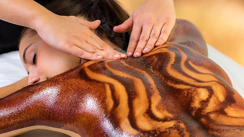 Der Rücken einer Frau ist während einer entspannenden Massage mit einer Schokoladenschicht bedeckt