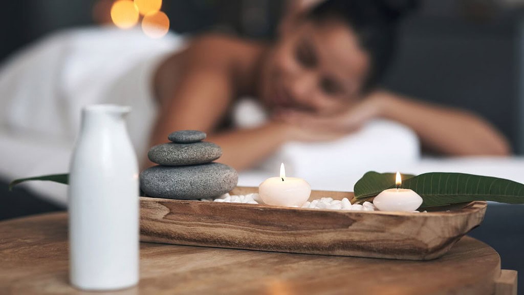 spa-beauty-erlebnis Eine Frau wird bei Kerzenlicht mit Ölen massiert