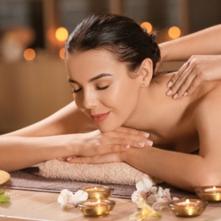 Eine Frau genießt eine winterliche Massage mit Kerzenlicht in einem Spa