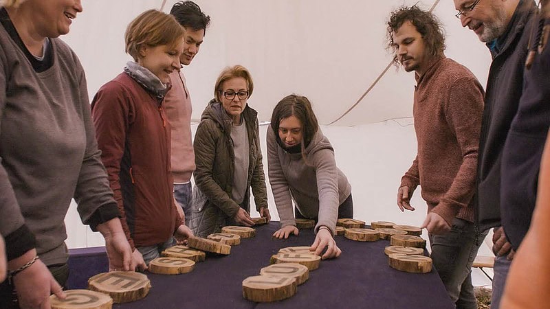 Viele Menschen bemühen sich, bedruckte Holzscheiben mit Buchstaben in die richtige Reihenfolge zu bringen