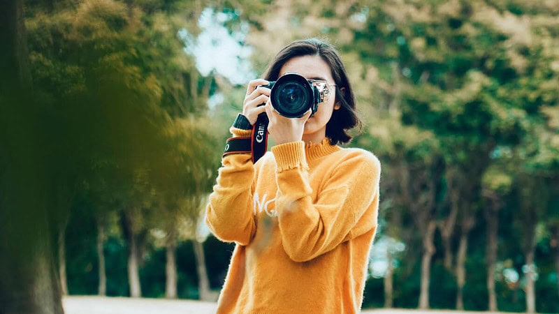 Eine Frau macht Fotos mit ihrer Kamera im Park