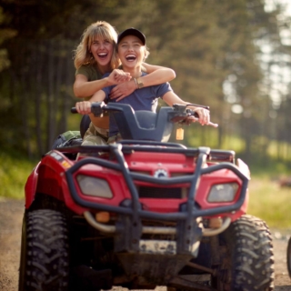 zwei Frauen fahren zusammen mit einem Quad, sie haben Spaß und lächeln