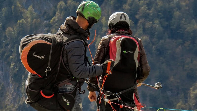 2 Personen, die sich auf dem Gipfel eines Berges auf einen Gleitschirmflug vorbereiten