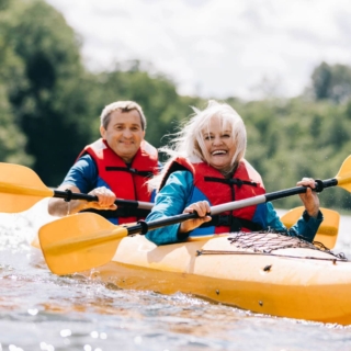 ausgefallene-geschenke-fuer-eltern ein lachendes älteres Paar fährt zusammen Kajak