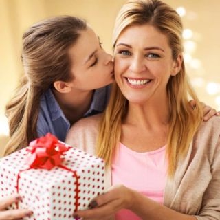 eine Frau erhält ein Geschenk von ihrer Tochter und lächelt