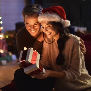 Eltern öffnen das Geschenk, das sie von ihren Kindern zu Weihnachten bekommen haben und lächeln
