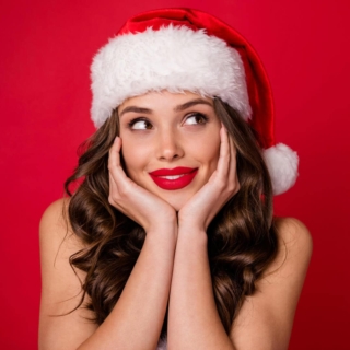 Frau mit Weihnachtsmannmütze posiert für ein Foto