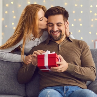 Ein Mann bekommt ein Geschenk zu Weihnachten von seiner Frau und lächelt