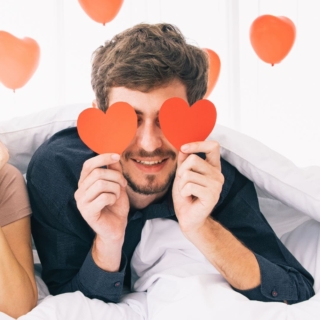 Ein Mann posiert mit Herzen aus Karton für ein Fotoshooting zum Valentinstag