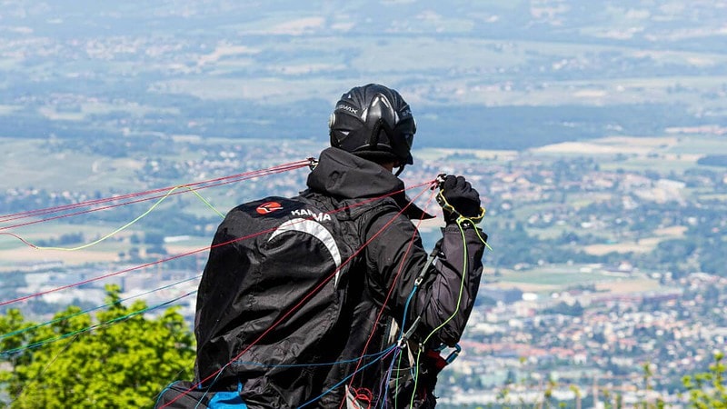 Mann auf dem Gipfel eines Berges, der sich auf einen Gleitschirmflug vorbereitet