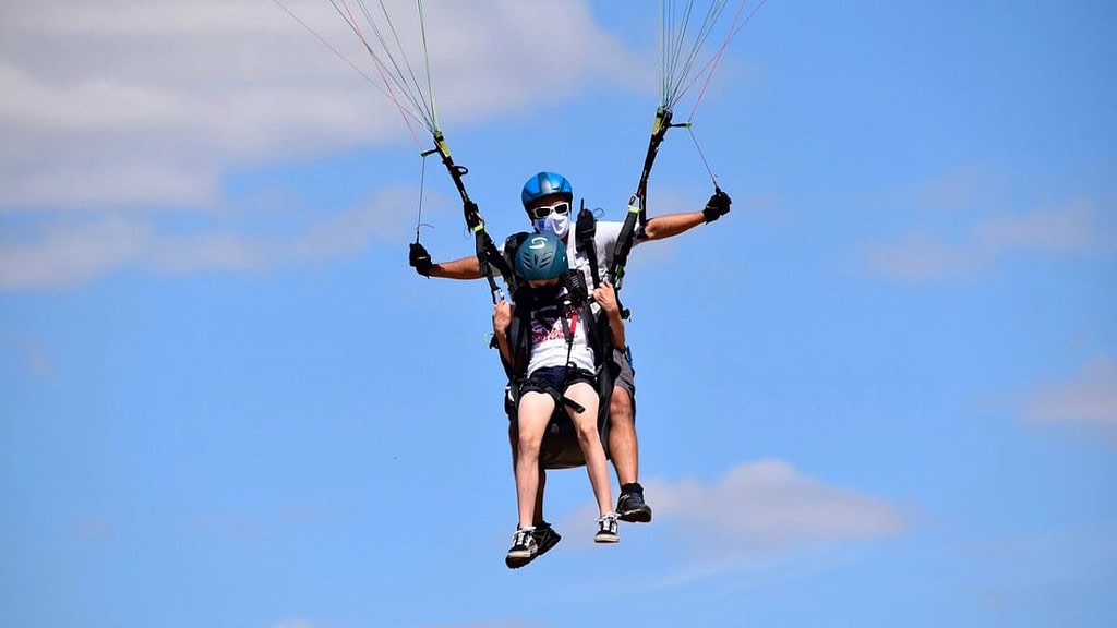 gleitschirm_kinder-2.jpeg Ein Pilot eines Gleitschirms fliegt zusammen mit einem Kind. - Gleitschirm Tandemflug für Kinder am Ossiachersee