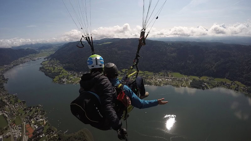 2 Personen fliegen zusammen mit einem Gleitschirm während Sonnenuntergang