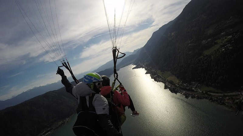2 Personen fliegen zusammen mit einem Gleitschirm während Sonnenuntergang