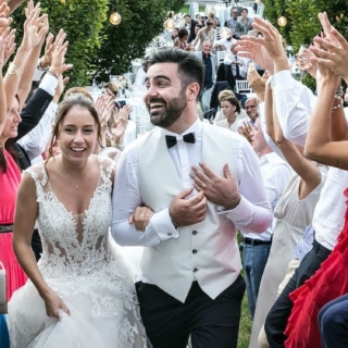 Ein Paar läuft in Hochzeitstracht durch eine jubelnde Schlange ihrer Gäste.