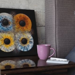 iris_fotoshooting_familie_web-18.jpeg Die 4 miteinander kollidierenden Iriden sind auf einer dunklen Leinwand verewigt worden, das Bild steht an die Wand gelehnt auf dem Nachttisch