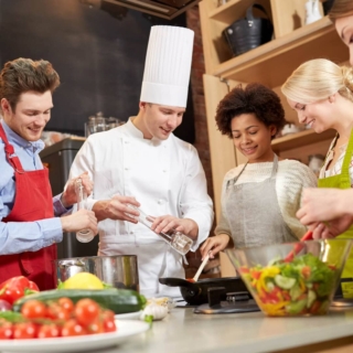 kochkurse-erlebnisse (1) eine Gruppe von Kochkursteilnehmern kocht unter der Aufsicht eines erfahrenen Kochs