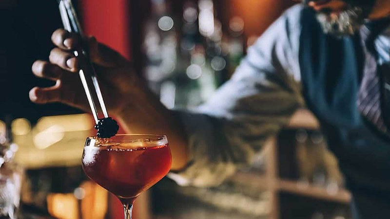 Ein Barkeeper setzt eine Brombeere auf ein Cocktail