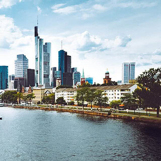 Blick auf Frankfurt am Morgen, mit dem Fluss im Vordergrund und den Wolkenkratzern im Hintergrund