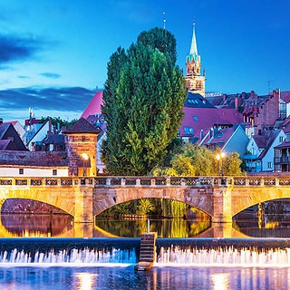 Blick auf die bunte Stadt Nürnberg, beleuchtete Brücke im Vordergrund
