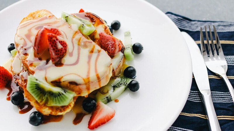 Dessert bestehend aus Brot, weißer Schokoladensauce, Karamell und Obst