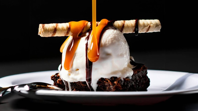 Brownie serviert mit einer Kugel Eis, überzogen mit Karamellsauce