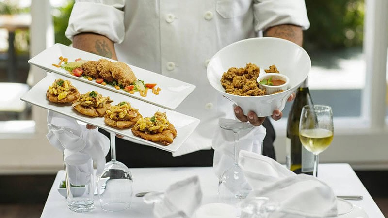 Chefkoch serviert 3 Gerichte und Wein am Tisch