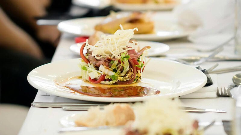 dekorierter Teller mit Essen, Restaurant und Besteck im Hintergrund