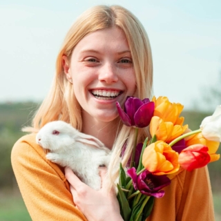 Eine Frau posiert für ein Fotoshooting zum Thema Ostern und hält Blumen und einen Hasen in den Händen