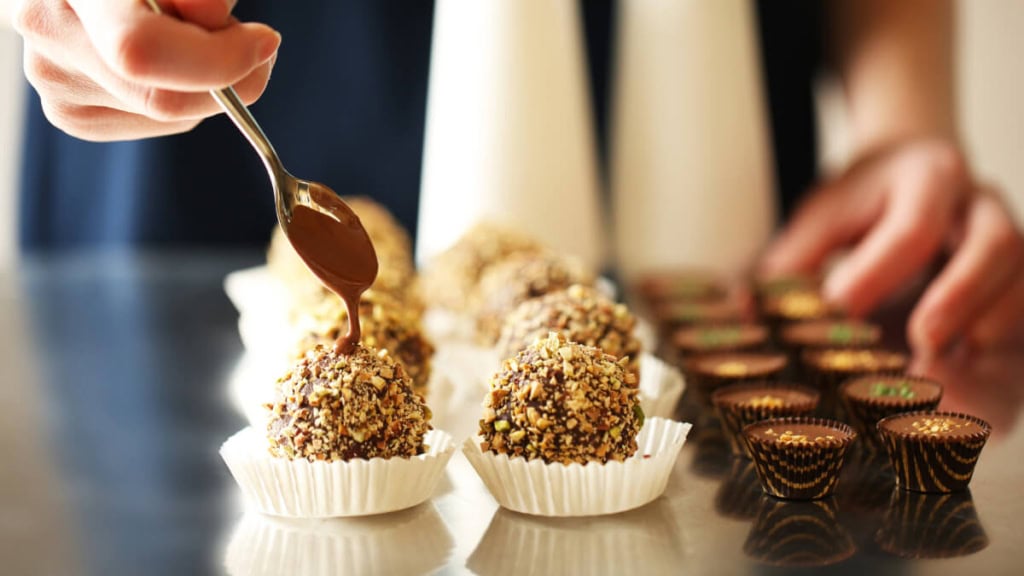 pralinen-seminar (1) Eine Person dekoriert die selbstgemachten Pralinen