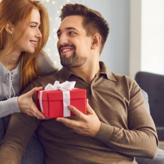 top-geschenke-dresden-maenner Ein Mann bekommt ein Geschenk von seiner Frau und lächelt