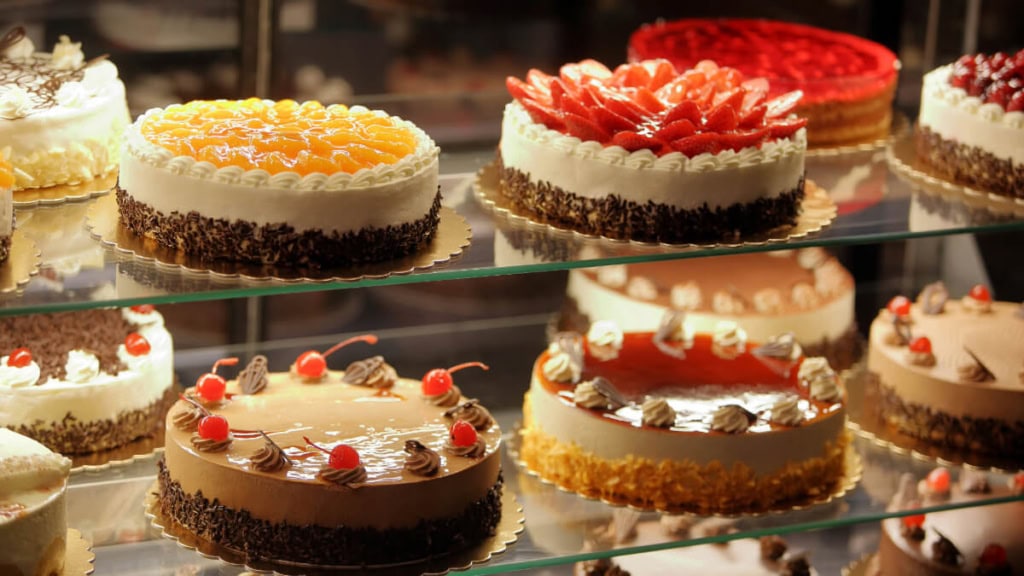 torten-seminar (1) Vielfalt von selbstgemachten dekorierten Torten auf einer Küchenvitrine
