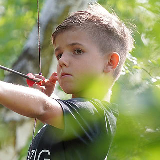 Ein Junge zielt mit einem Bogen auf eines der Ziele beim 3D Bogenparcours bei Leipzig.