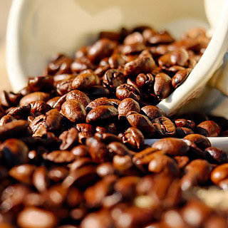 Aus einer umgekippten Tasse sind Kaffeebohnen verteilt.