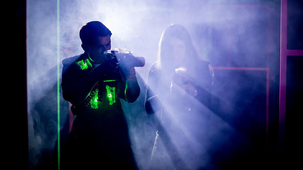 Lasertag Düsseldorf 2 Spieler Ein Junge und ein Mädchen die im Nebel stehen und ein Lasertag Gewehr in den Händen halten.