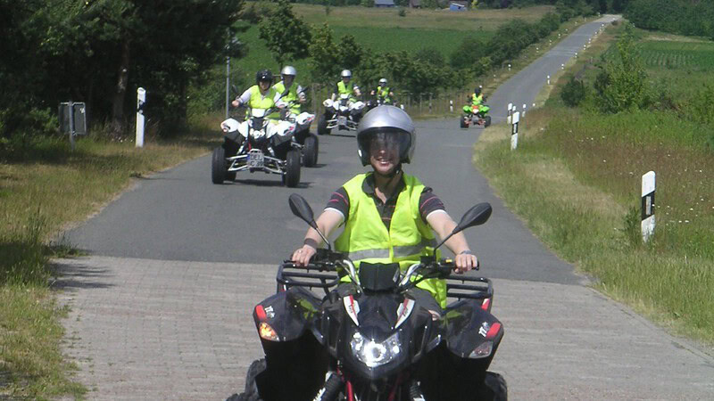 Quadkolonne mit gelben Warnwesten fahren auf einer Landstraße