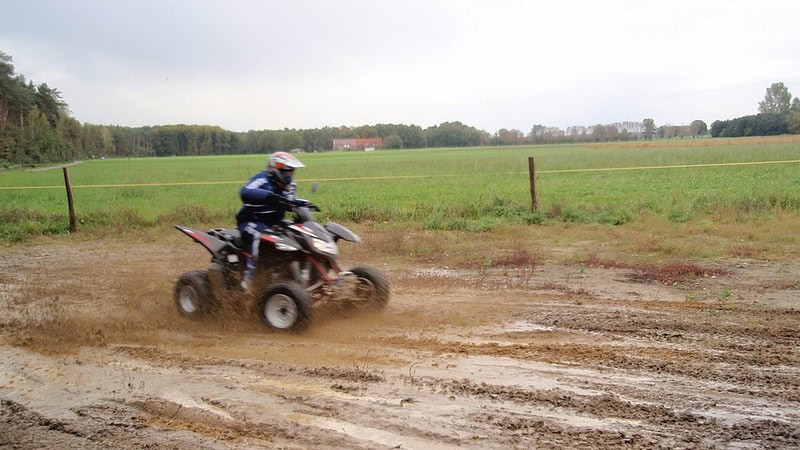 Ein Quadfahrer heizt durch Schlammigen Feldweg