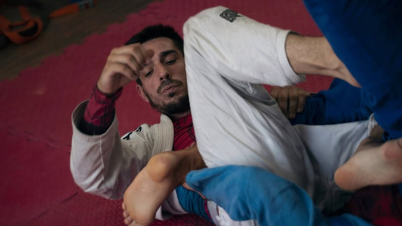 Mann mit weißer Hose liegt auf roter Matte