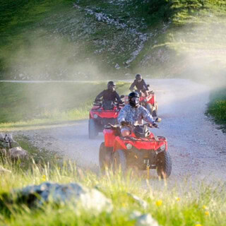 3 Quads auf einem Schotterweg 3 rote Quads auf einem Schotterweg zwischen Hügeln