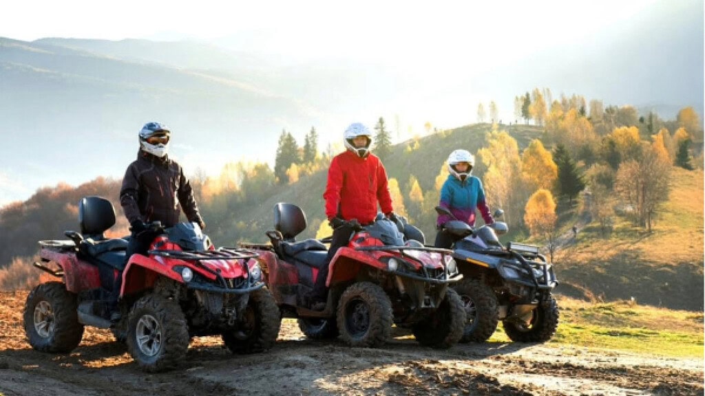 3 Quads in einer schönen Landschaft 3 Quad Fahrer die auf ihren Quads auf einem Berg stehen.