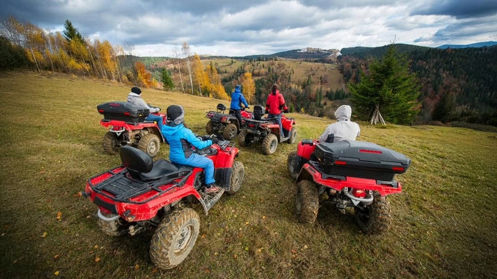 5 Quads auf einer steilen Wiese 5 Quad Fahrer die eine schräge Wiese hinunter schauen.