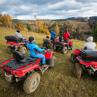 5 Quads auf einer steilen Wiese 5 Quad Fahrer die eine schräge Wiese hinunter schauen.