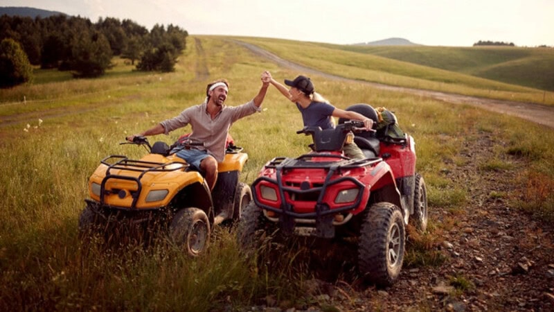 Ein Paar auf 2 Quads welches die Hände freudig hält und sich an lacht.