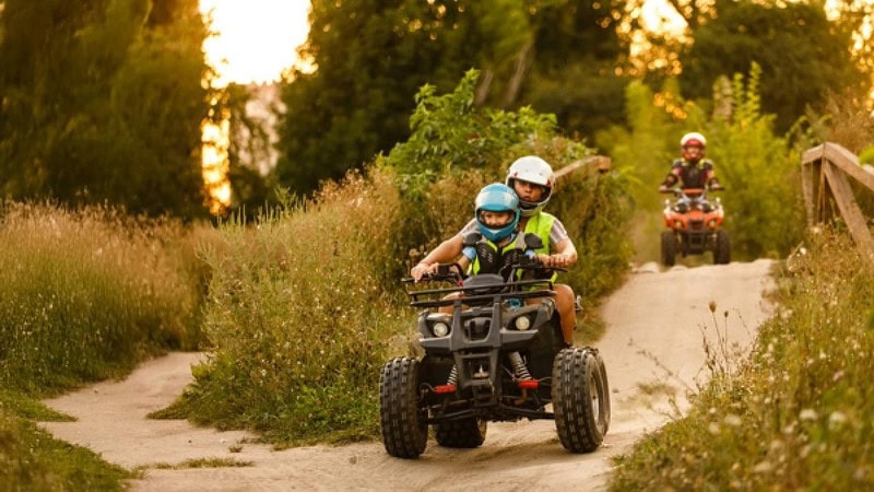 Ein Vater der mit seinem Sohn Quad fährt.