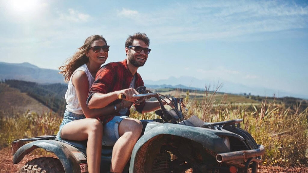 lachendes paar auf einem Quad Ein Paar welches zusammen auf einem Quad fährt und lacht.