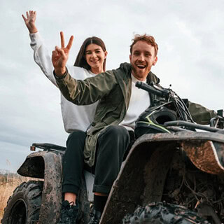 paar posed auf Quad vor Kamera Ein Mann und eine Frau auf einen Quad die lachen und Peace mit ihren Händen zeigen.